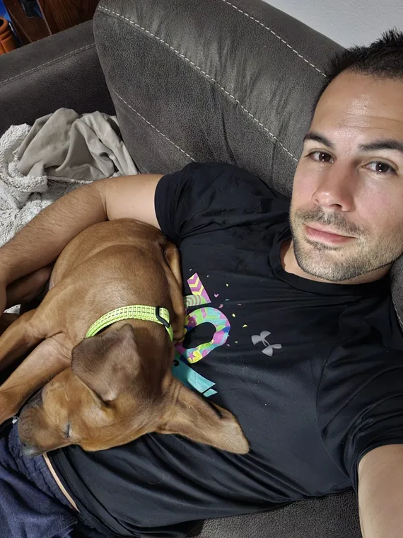 Arwen curled up asleep beside a person on a sofa.